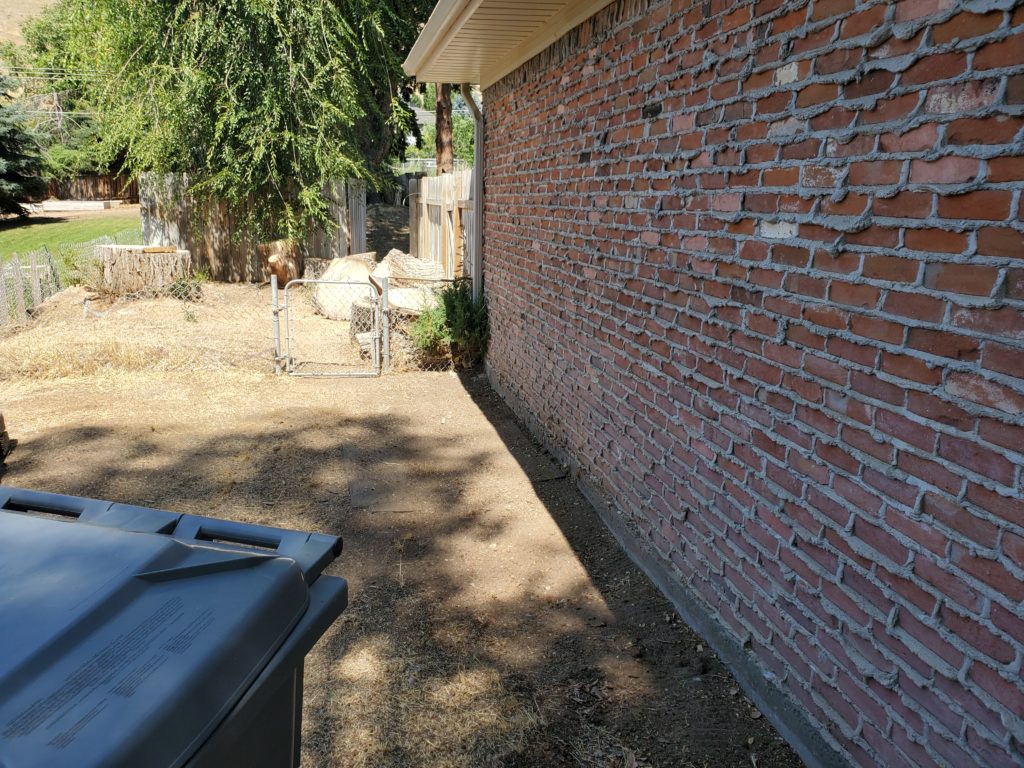 Image of brick wall after removing stack of logs